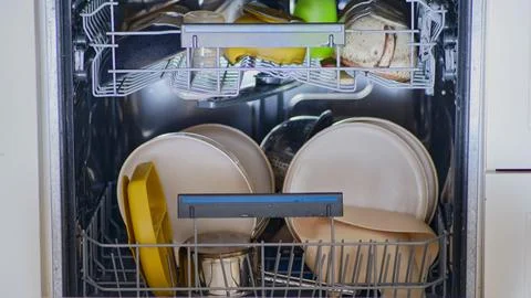 Loading dirty dishes into the dishwasher, stop motion. Filling the dishwasher Fotos de archivo