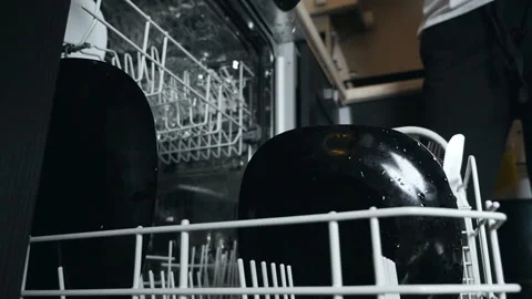 Loading the dishwasher to put dishes and kitchen utensils in the basket, hands Stock Footage 128605235