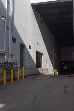 Loading dock outside a white block building with inclined street Stock Photos