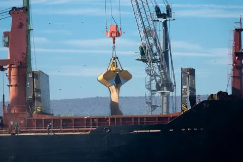 Loading dry cargo ship of wheat by cranes in port. Loading into holds of se.. Stock Photos