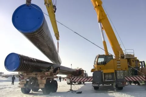 Loading of gas pipes onto a conveyor using a manipulator with a crane. Stock Photos