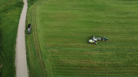 Loading hay with a combine into a tractor trailer Stock Footage 218345840
