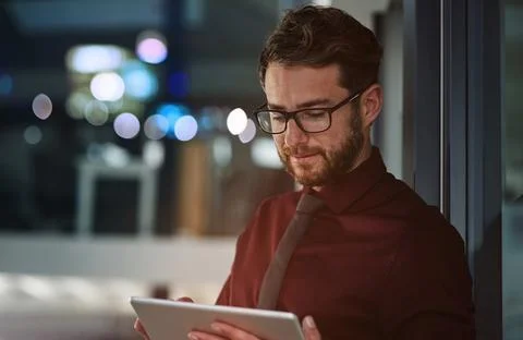 Loading his tablet with business apps. a young businessman using a digital Stock Photos