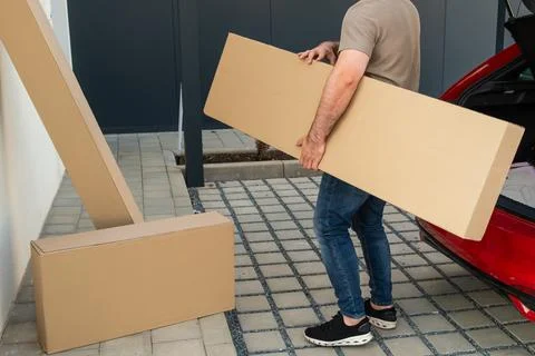 Loading large cardboard boxes into vehicle trunk at home delivery station Fotos Stock