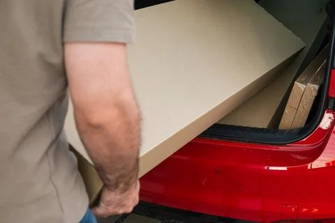 Loading large cardboard sheets into vehicle trunk for home improvement project Stock Photos