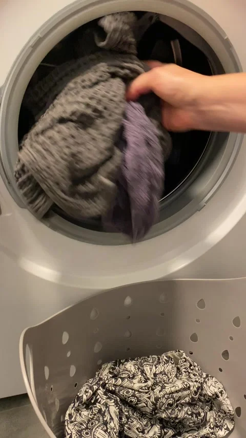 Loading laundry into washer for fresh cycle Видео 343864268