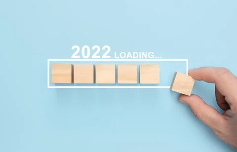 Loading new year 2022 with hand putting wood cube in progress bar. Loading ne Stock Photos