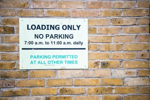 Loading only no parking sign on brick wall Foto stock
