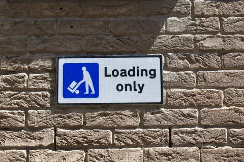 Loading only sign in blue and white on a brick wall. Stock Photos
