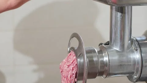 Loading pieces of pork and veal into electric industrial grinder for processing Video stock 322940853