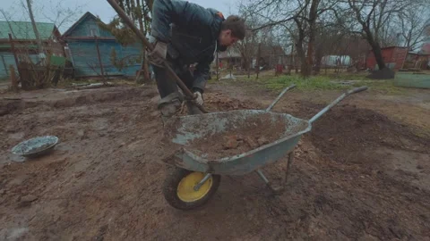 Loading rocks into a wheelbarrow Видео 333014977