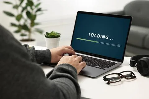 Loading screen displaying progress. Man working on laptop at table indoors,.. Stockfoto's