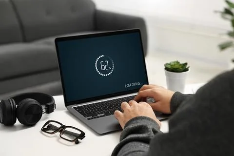 Loading screen displaying progress. Man working on laptop at table indoors,.. Fotos de archivo
