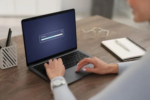 Loading screen displaying progress. Woman working on laptop at table indoor.. Stockfoto's