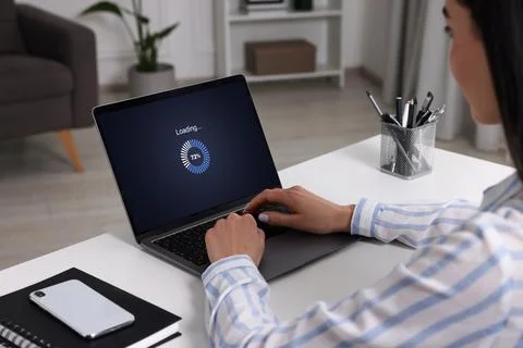 Loading screen displaying progress. Woman working on laptop at table indoor.. Stock Photos