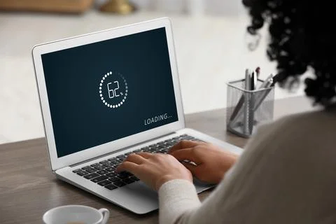 Loading screen displaying progress. Woman working on laptop at table indoor.. Foto stock