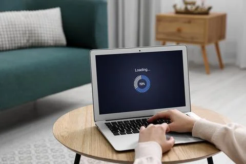 Loading screen displaying progress. Woman working on laptop at table indoor.. Stockfoto's