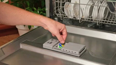 Loading the tablet into the dishwasher. A man puts tablet in the dishwasher to Stock Footage 245657502