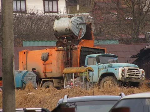 Loading Waste Containers into Vintage Orange Garbage Truck Foto stock