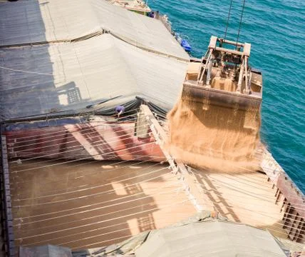 Loading wheat on cargo ship with crane and bucket. Shipment from a merchant s Stock Photos