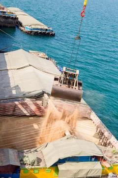 Loading wheat on cargo ship with crane and bucket. Shipment from a merchant s Stock Photos