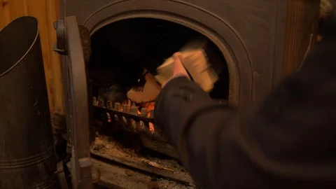 Loading up wood burner stove with logs MID SHOT 4K Stock Footage 127779241