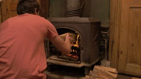 Loading wrought iron stove with silver birch logs self reliant young man Video stock 141748398