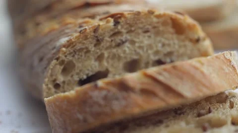 Loaf and slices of bread with grains on white background. Close up slow panorama Stock Footage 50362986