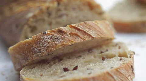 Loaf and slices of bread with grains on white background. Close up slow panorama Stock Footage 50362989