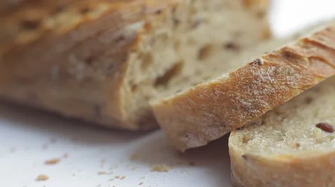 Loaf and slices of bread with grains on white background. Close up slow panorama Stock Footage 50362999
