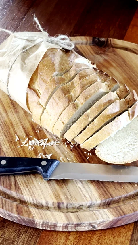 Loaf of bread from bakery cut into slices on wooden cutting board Stock Footage 344010878