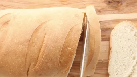 A loaf of bread being sliced into even pieces, revealing its soft, airy texture. 스톡 동영상 311012492
