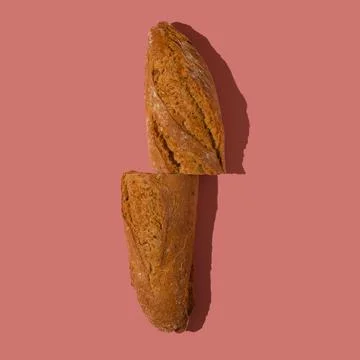 Loaf of bread cut in half on a pastel pink background. Stock Photos