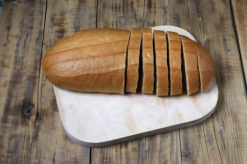 A loaf of bread is cut into pieces on a cutting board. Stock-Fotos