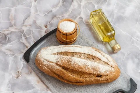 Loaf of bread on cutting board and sunflower oil on kitchen desk Stock Photos