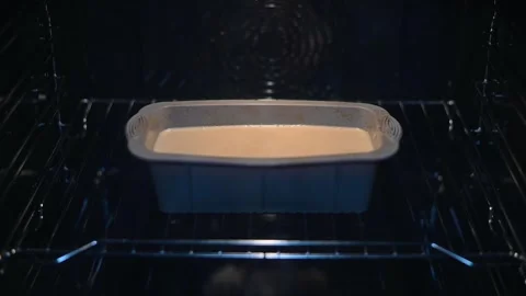 A loaf of bread dough is placed in an oven, where it rises and begins to brown. Stock Footage 339097363