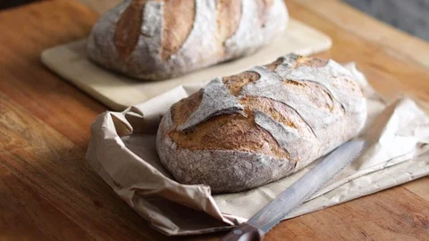 Loaf of bread with a knife on a wood table 스톡 동영상 128305855