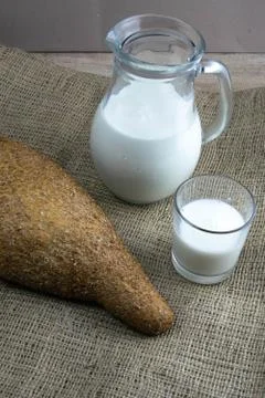 A loaf of bread with milk and butter dough stands on a craft linen bag. Stock Photos