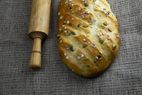 A loaf of bread with a rolling pin for dough stand on a craft linen bag. Stock Photos