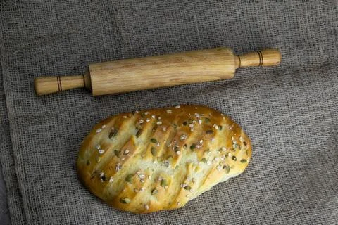 A loaf of bread with a rolling pin for dough stand on a craft linen bag. Stock Photos