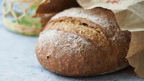 A loaf of bread sits on a table wrapped in paper Stock Footage 344890564