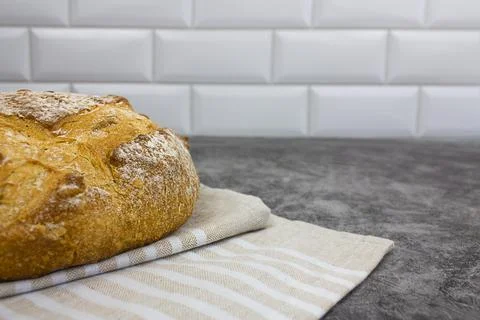 A loaf of bread on a towel on a light background. Copy space. Stock Photos