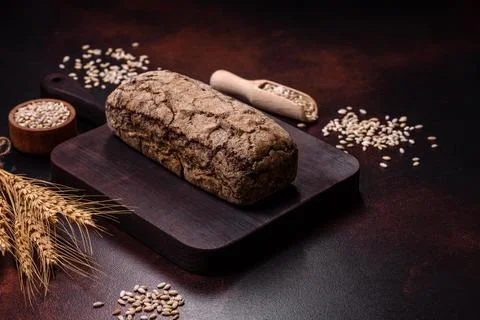 A loaf of brown bread with grains of cereals on a wooden cutting board Stock Photos