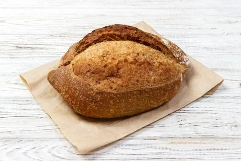 Loaf of fresh baked wheat bread on old wooden table Stock Photos
