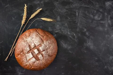 Loaf of fresh bread and wheat on a black table. Top view with copy space. Bakery Stock Photos