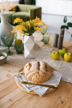 A loaf of fresh bread on the breakfast table, mimosa flowers in a vase Stock Photos