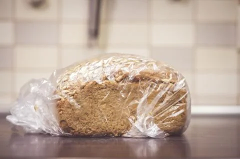 Loaf of fresh bread in a plastic bag on the table Stock Photos