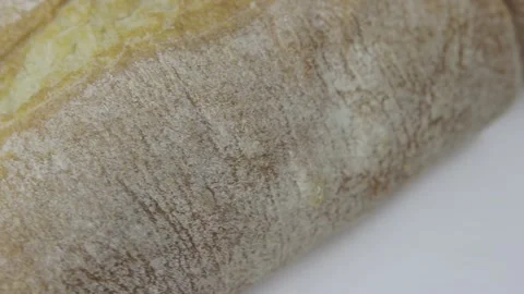 Loaf of fresh wheat bread and a slice rotate on a white background Stock Footage 131074383