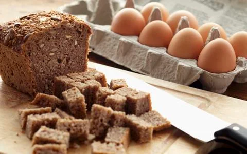 Loaf of Nut Bread with Pieces Cut in Large Cubes and a Carton of Eggs Stock Photos