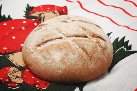 A loaf of round bread with a pattern on a bright tablecloth Stock Photos